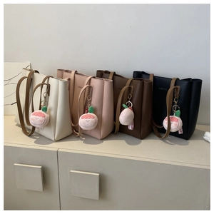 Four tote bags in beige, pink, brown, and black with peach charms on a white background