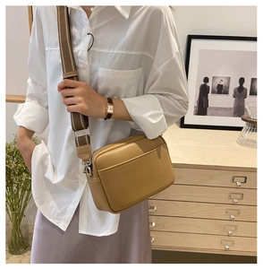 Lifestyle shot of minimalist khaki crossbody bag with wide striped strap on model