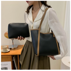 Detail of two-piece black leather tote bag with brown contrast trim shown in lifestyle setting