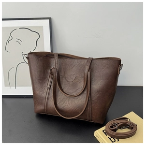Detail of dark brown tote bag showing textured faux leather and adjustable shoulder strap