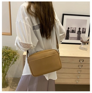 Detail view of a camel leather crossbody bag with zipper and adjustable strap