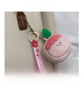 Pink plush keychain with Sweet strap shown as an accessory on a white leather bag