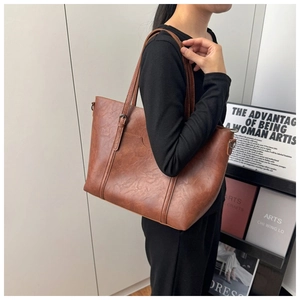 Detail of vintage brown tote bag with leather texture and metal strap hardware