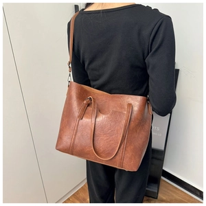 Rear view of a model wearing a large vintage brown tote bag in textured PU leather