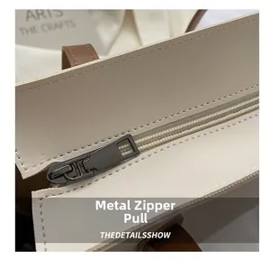 Detail of high-quality metal zipper and leather texture on a beige tote bag