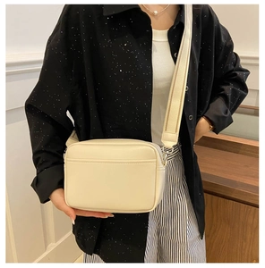 Detail of off-white minimalist camera bag with adjustable wide fabric shoulder strap