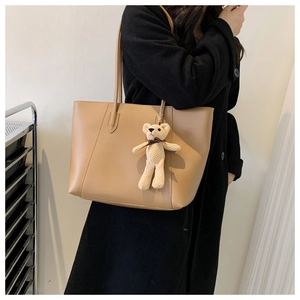 Close-up of khaki oversized tote bag with cute bear charm for daily commute and styling