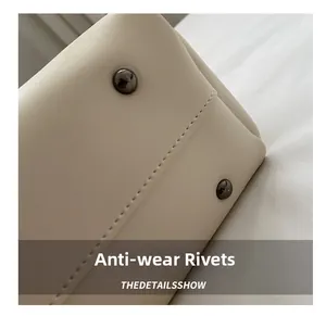Close-up of anti-wear rivets on cream leather tote bag with fine stitching detail