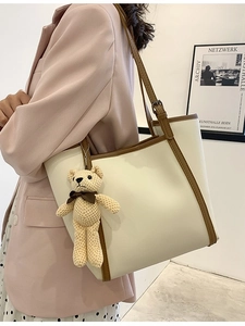 Minimalist beige and brown tote bag with teddy bear pendant shown on shoulder