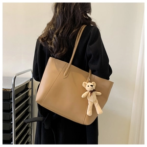 Detail of a large khaki tote bag with a cute bear charm shown from a back-view perspective