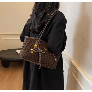 Sac cabas léopard marron foncé avec logo doré et pendentif sur fond d'intérieur chic