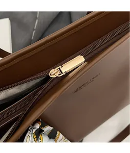 Close-up of golden zipper and embossed fashion leather text on brown tote bag