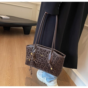 Gros plan du sac cabas léopard avec logo doré porté avec un manteau d'hiver noir