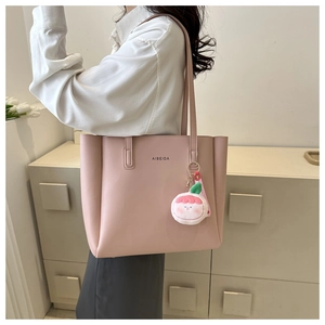 Detail of light pink tote bag with AIBEIDA logo and a cute peach plush charm detail