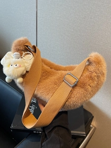 Brown faux fur crescent shoulder bag with canvas strap and plush monster charm
