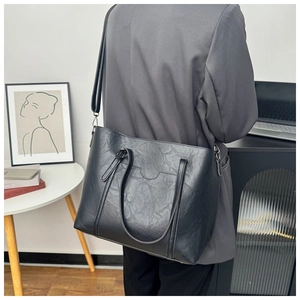Close-up of black leather tote bag with lychee texture and adjustable shoulder straps