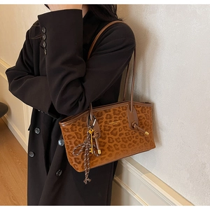 Gros plan d'un sac cabas léopard avec manteau noir et breloque décorative en clé