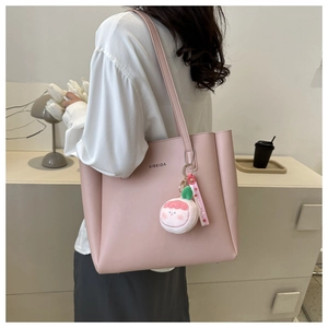 Pink leather tote bag detail with plush charm and side profile shown on model