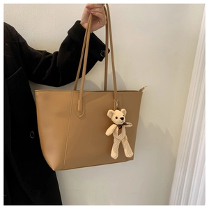 Detail of khaki PU leather tote bag with knitting bear charm and zip closure for work