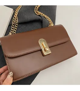 Close-up of brown leather bag featuring a gold rectangular twist lock and thick chain