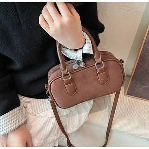 Braune Tasche aus Wildleder und Leder mit silbernen Beschlägen, von einem Model getragen