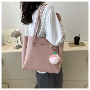 Pink tote bag detail featuring premium texture, long handles and a cute peach plush charm