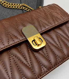 Close-up of brown quilted leather bag featuring a gold rectangular twist lock and metal chain