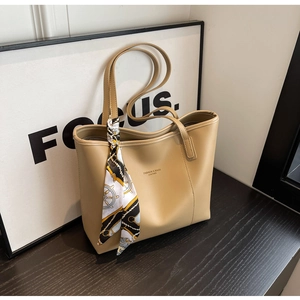 Detail of khaki leather tote bag with geometric silk scarf tied on the handle