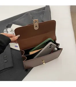 Detail view of brown leather bag with dual compartments for large phones and makeup