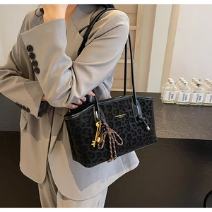 Détail du sac cabas léopard avec lettrage doré et bijou de sac sur blazer gris