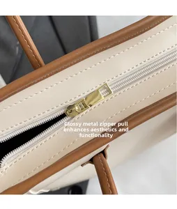 Detailed close-up of smooth gold zipper hardware on beige and brown tote bag