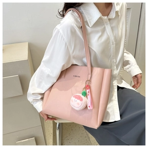 Side view of pink tote bag with peach plush charm and shoulder strap on model