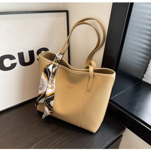 Detail of khaki tote bag in matte leather featuring a decorative printed silk scarf on handle