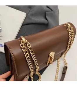 Detailed close-up of brown leather bag featuring a premium golden rotary lock and chain strap