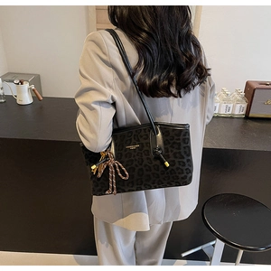 Détail du sac cabas léopard avec des accents de boules dorées et un charme tissé