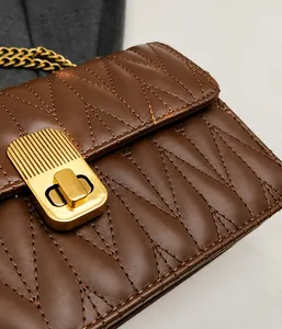 Close-up of brown quilted shoulder bag featuring gold chain and metallic twist lock