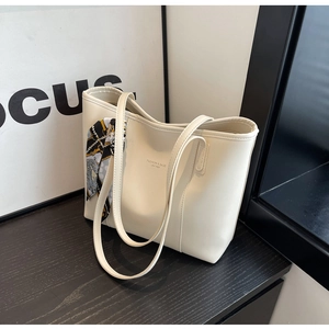 Detail of cream tote bag with leather embossing and elegant decorative silk scarf
