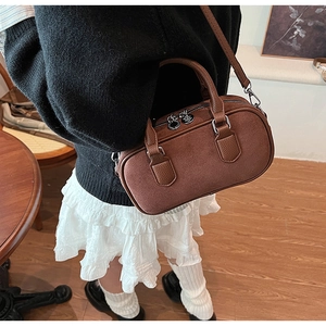 Detail view of brown retro Boston bag featuring silver double zippers and荔枝 grain texture