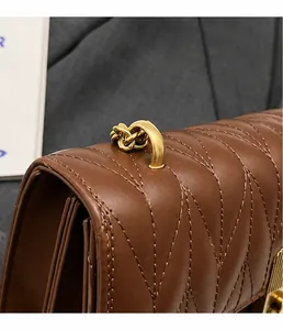 Macro detail of brown quilted leather bag with matte gold rings and accordion side structure
