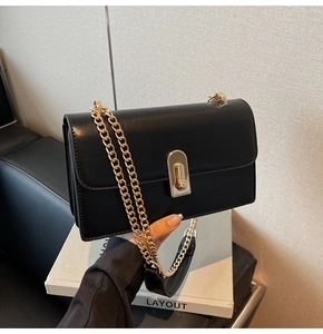 Detail of black matte leather shoulder bag with gold chain strap and metal turn-lock