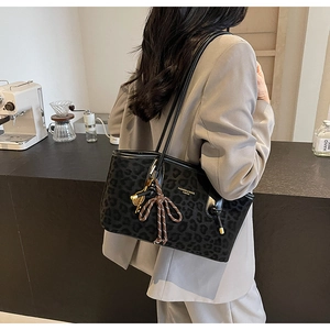 Détail du sac cabas léopard avec nœud tressé et pendentif clé dorée sur l'épaule