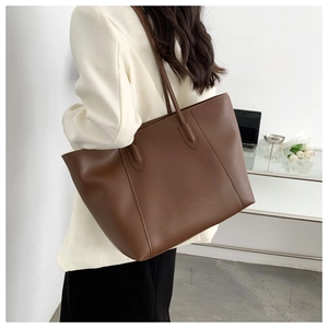 Brown leather tote bag shown on model in an office setting for size perspective
