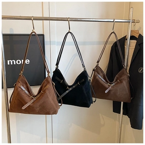 Close-up of three retro suede tote bags in caramel, black, and coffee on a metal hanger
