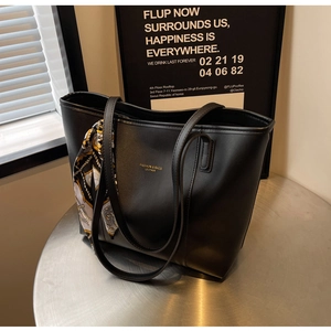 Detail of black leather tote bag with fashion lettering and decorative silk scarf on handle