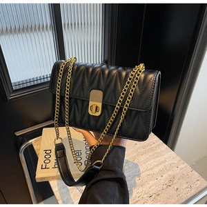 Detailed close-up of quilted black leather handbag with gold chain strap and turn-lock