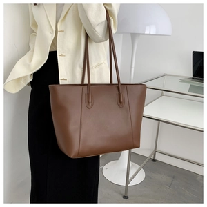 Brown leather large tote bag shown on shoulder of model in professional white blazer