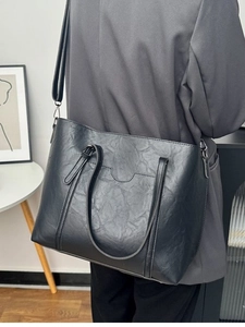 Vintage black faux leather tote bag shown on model with shoulder strap and large capacity