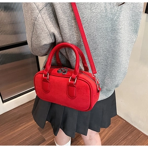 Detail view of red suede top handle bag with leather straps and double zipper design