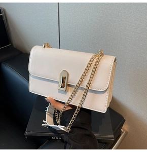 Detail of white faux leather bag featuring a gold twist lock and fine metal chain strap