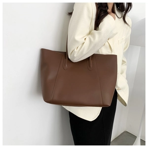 Side view of a large brown tote bag in smooth leather on a model for daily commute